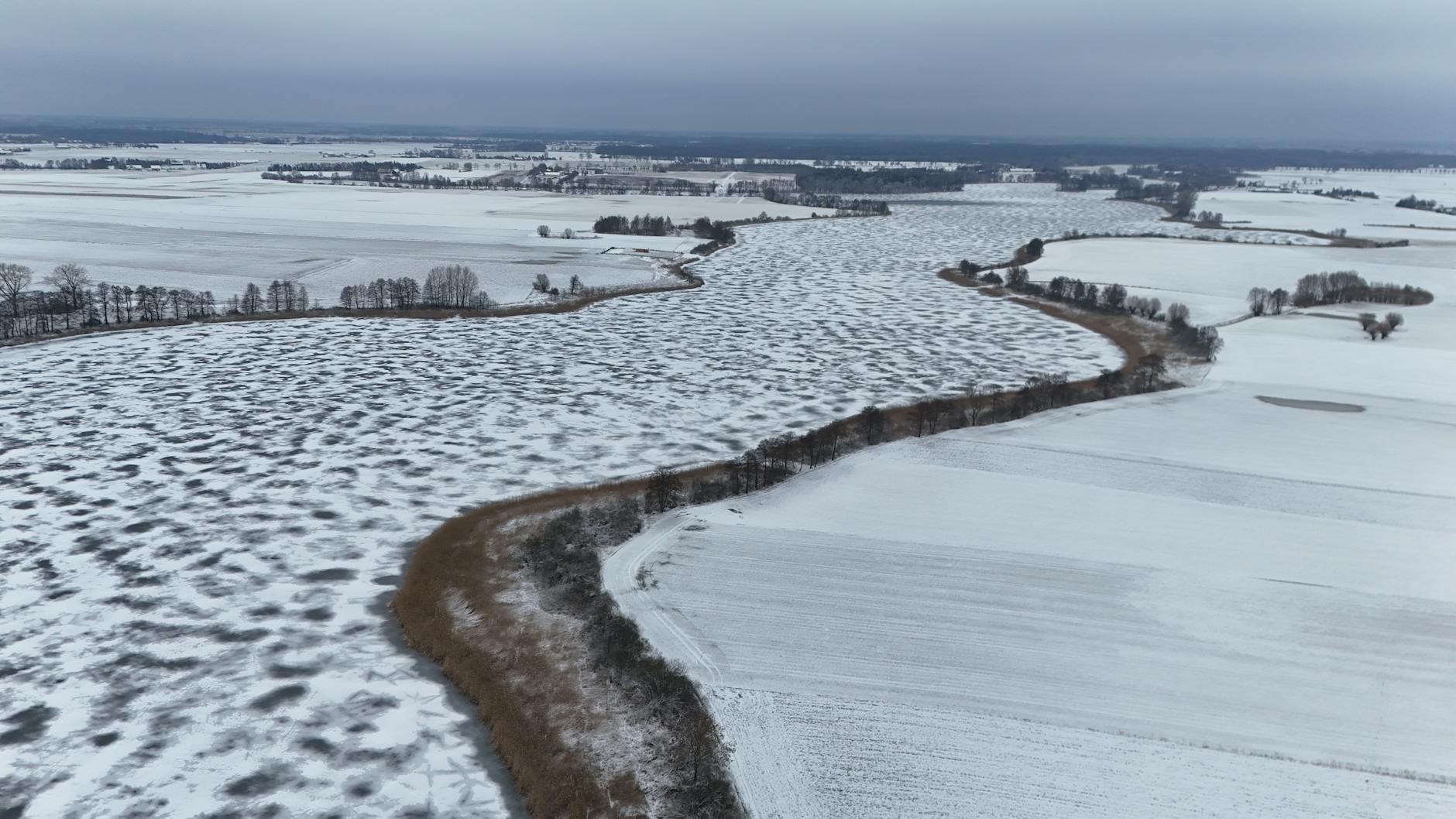 Zimowy pejzaż Suwalszczyzny z zaśnieżonymi polami i wijącą się rzeką