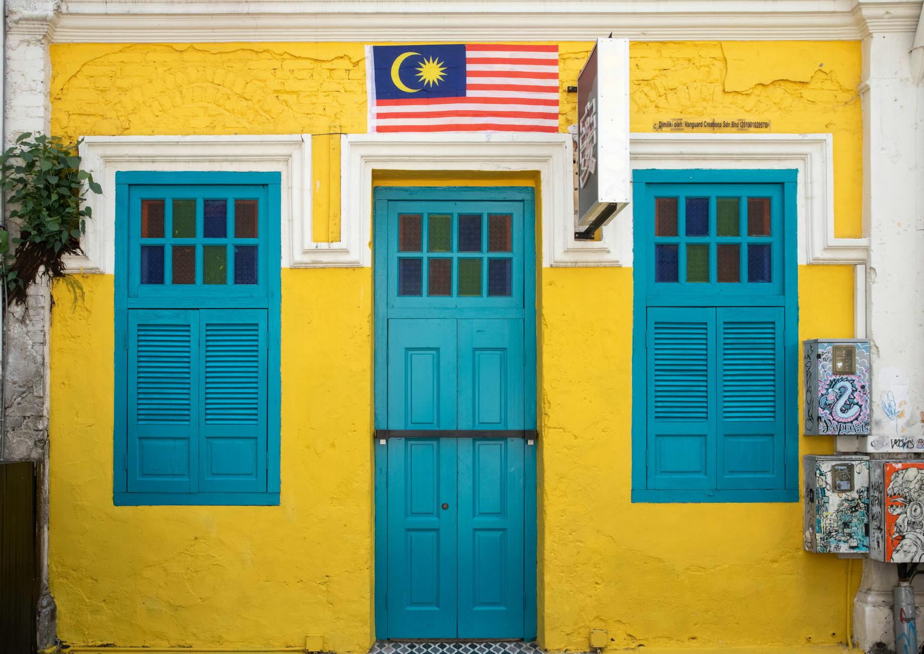 Żółto-turkusowa fasada budynku z flagą Malezji