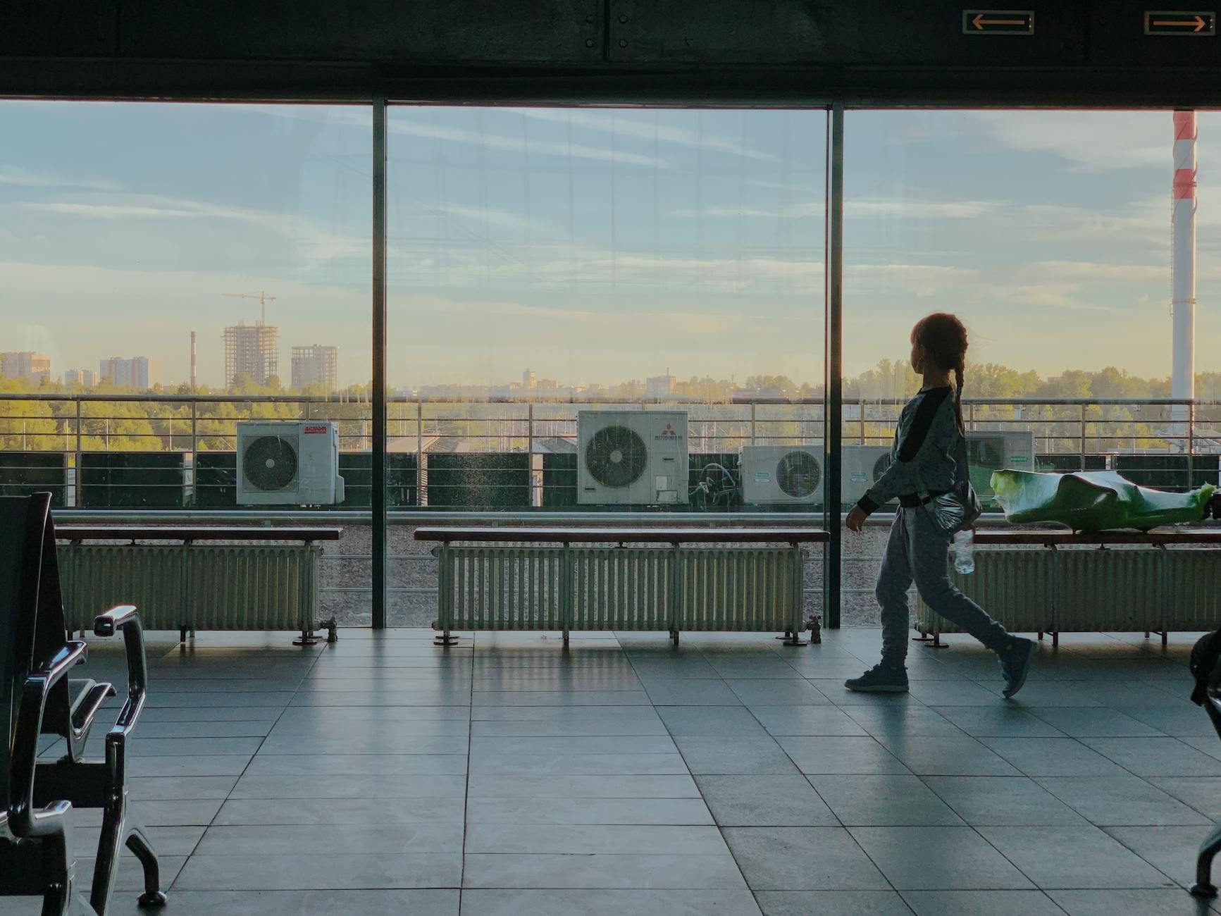 Dziecko spaceruje po nowoczesnym terminalu lotniska z widokiem na miasto