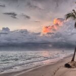 Zachód słońca nad plażą Punta Cana z palmami i chmurami